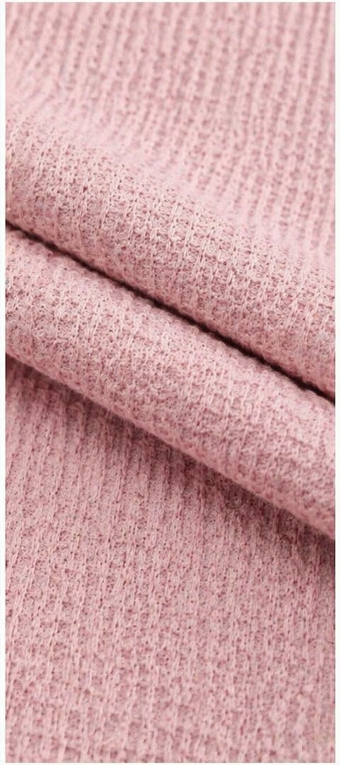 Close-up of pink waffle-knit fabric made from 95% polyester and 5% spandex, highlighting the raised textured weave pattern and lightweight, stretchy material